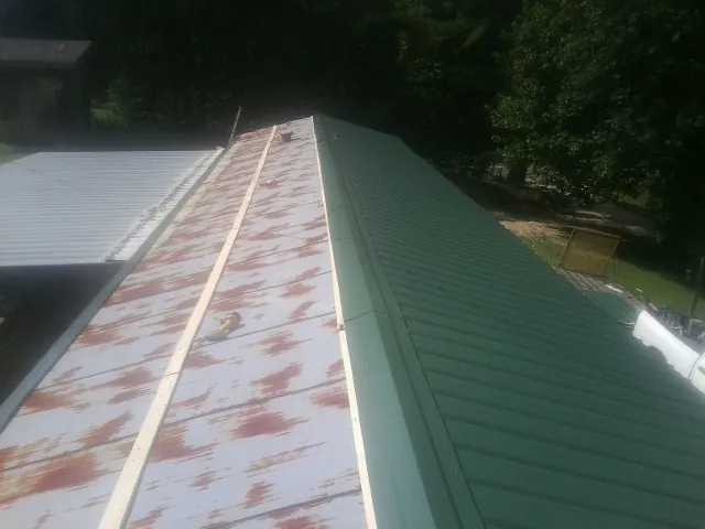 Old rusted panels beside newly installed green metal roofing — Wind Damage Roof Repair by Roofing Brothers in Kramer