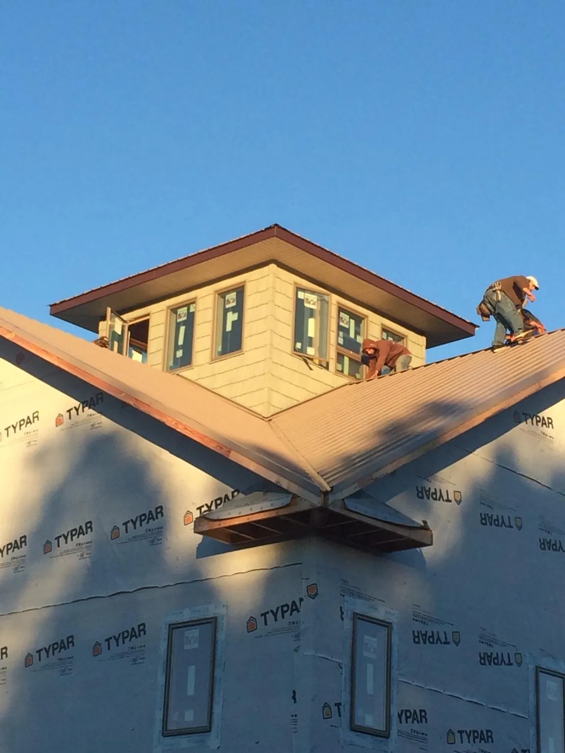 Roofers working around a rooftop cupola on a new metal roof at sunset — Roof Waterproofing in Kramer by Roofing Brothers